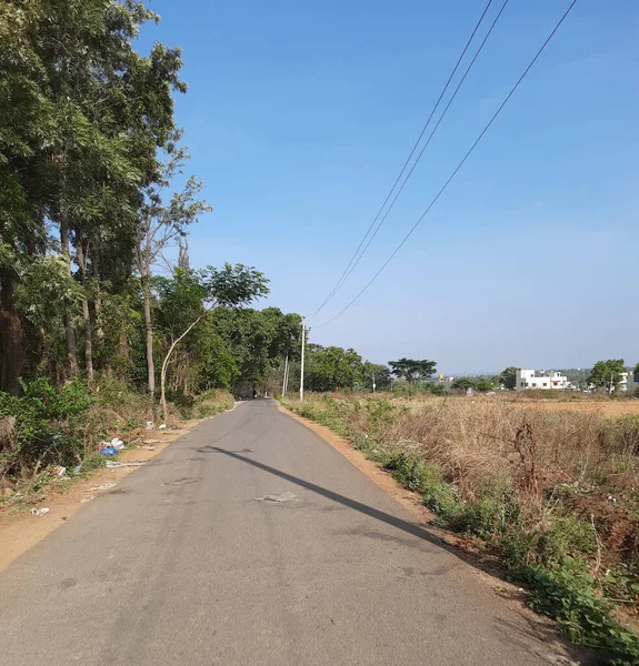 2021年5月9日インド カルナータカ州バンガロール 美しいバンガロール農村部の道路が閉鎖され 電柱と木が道路に影を落としています 自転車に乗ってる若い男 — ストック写真