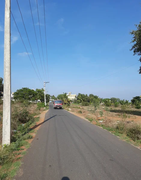 2021年5月9日インド カルナータカ州バンガロール 美しいバンガロール農村部の道路が閉鎖され 電柱と木が道路に影を落としています 自転車に乗ってる若い男 — ストック写真