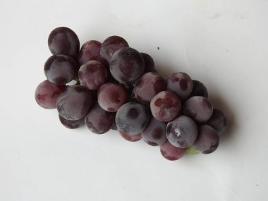 Güzel koyu kırmızı ve siyah üzüm meyvelerinin yakın plan resmi beyaz arka planda izole edilmiş.