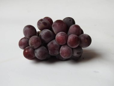 Güzel koyu kırmızı ve siyah üzüm meyvelerinin yakın plan resmi beyaz arka planda izole edilmiş.