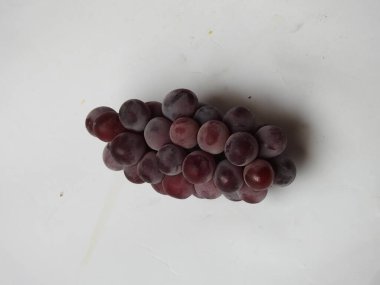 Güzel koyu kırmızı ve siyah üzüm meyvelerinin yakın plan resmi beyaz arka planda izole edilmiş.