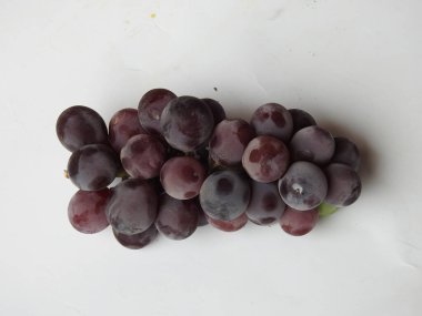 Güzel koyu kırmızı ve siyah üzüm meyvelerinin yakın plan resmi beyaz arka planda izole edilmiş.