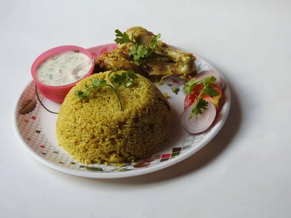 Closeup of beautiful restaurant style home made Chicken Biryani with two leg pieces and yogurt dip in a plate isolated on white background