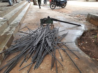 Bangalore, Karnataka, India-June 05 2021: Closeup of two indian young man wear mask and cutting the hexagon window rod manually in the road side during lockdown, covid 19 season