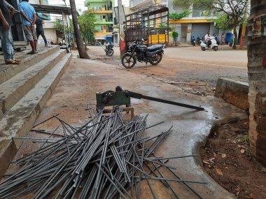 Bangalore, Karnataka, India-June 05 2021: Closeup of two indian young man wear mask and cutting the hexagon window rod manually in the road side during lockdown, covid 19 season