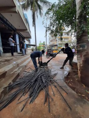 Bangalore, Karnataka, India-June 05 2021: Closeup of two indian young man wear mask and cutting the hexagon window rod manually in the road side during lockdown, covid 19 season
