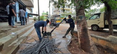 Bangalore, Karnataka, India-June 05 2021: Closeup of two indian young man wear mask and cutting the hexagon window rod manually in the road side during lockdown, covid 19 season