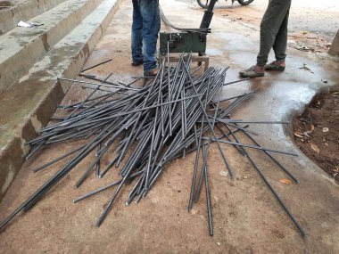 Bangalore, Karnataka, India-June 05 2021: Closeup of two indian young man wear mask and cutting the hexagon window rod manually in the road side during lockdown, covid 19 season