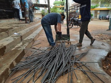 Bangalore, Karnataka, India-June 05 2021: Closeup of two indian young man wear mask and cutting the hexagon window rod manually in the road side during lockdown, covid 19 season