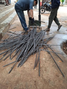 Bangalore, Karnataka, India-June 05 2021: Closeup of two indian young man wear mask and cutting the hexagon window rod manually in the road side during lockdown, covid 19 season