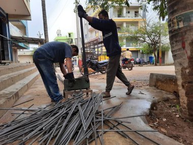 Bangalore, Karnataka, India-June 05 2021: Closeup of two indian young man wear mask and cutting the hexagon window rod manually in the road side during lockdown, covid 19 season