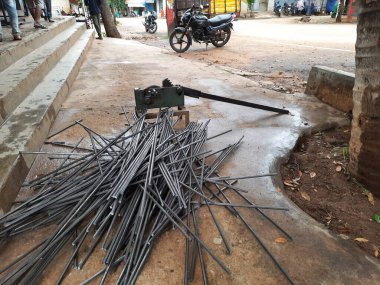 Bangalore, Karnataka, India-June 05 2021: Closeup of two indian young man wear mask and cutting the hexagon window rod manually in the road side during lockdown, covid 19 season