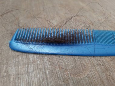 Mavi renkli plastik tarak ve günlük saç dökülmesi ya da saç dökülmesi ciddi bir sorun. Tarak beton zemin zemininde izole edildi