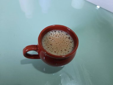 Tek kırmızı ya da kahverengi renkli kil, bir masada kum kahve fincanı.