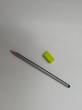 Siyah veya gri renkli kalem ve yeşil kauçuk eğitim kırtasiyesinin yakın plan resmi beyaz arkaplanda izole edildi