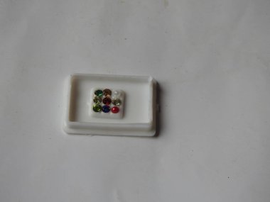 Gemstone 'un saf Navaratna Taşı Paketlemesi beyaz arka planda izole edilmiş plastik bir kutuda
