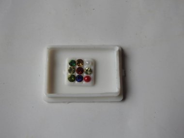 Gemstone 'un saf Navaratna Taşı Paketlemesi beyaz arka planda izole edilmiş plastik bir kutuda