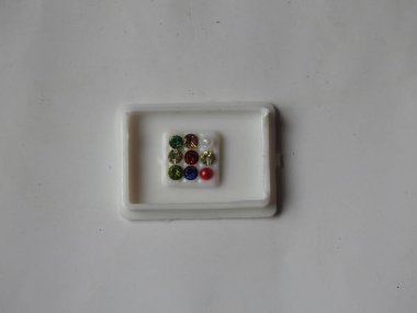 Gemstone 'un saf Navaratna Taşı Paketlemesi beyaz arka planda izole edilmiş plastik bir kutuda