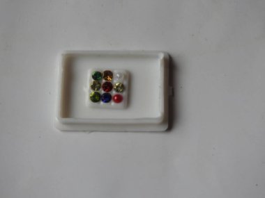 Gemstone 'un saf Navaratna Taşı Paketlemesi beyaz arka planda izole edilmiş plastik bir kutuda