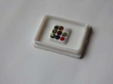 Gemstone 'un saf Navaratna Taşı Paketlemesi beyaz arka planda izole edilmiş plastik bir kutuda