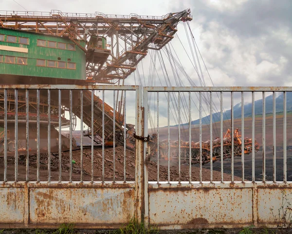 Enorme kolen mijnbouw kolen machine achter een ijzeren poort — Stockfoto