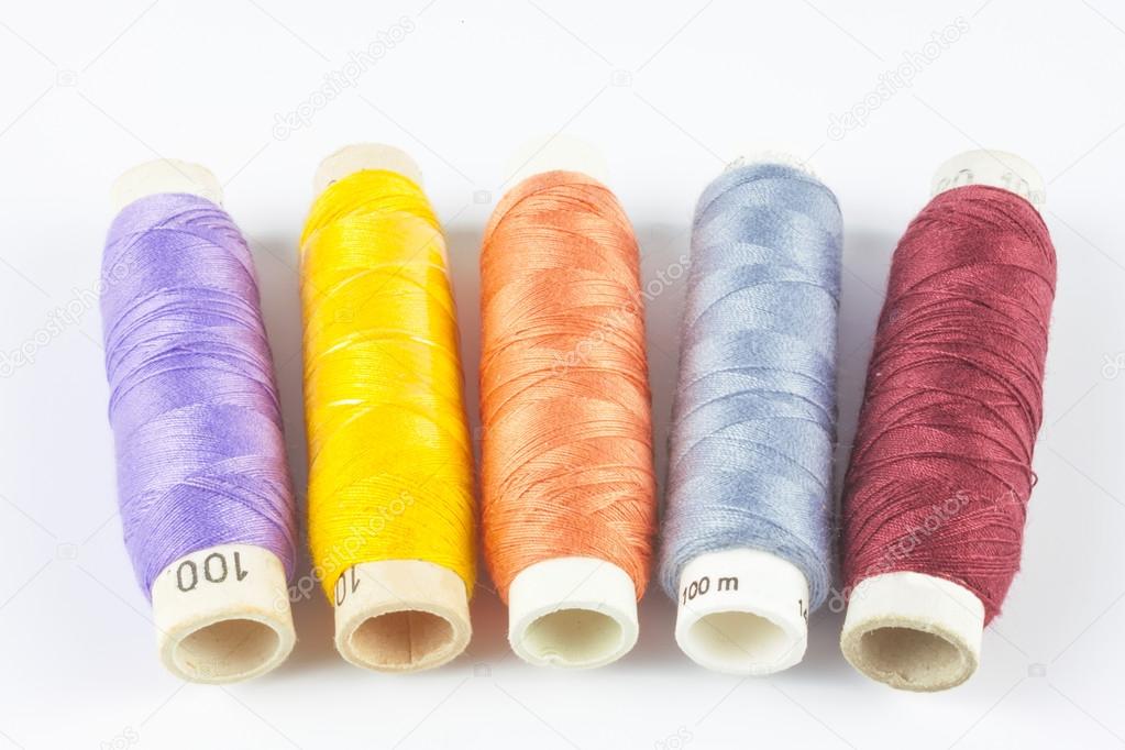 Coloured bobbins of thread on white background