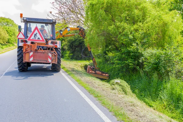 CZECH REPUBLIC, DOBRANY, 26 MAY, 2016:Tractor machine mowing grass along road. — Stock Photo, Image