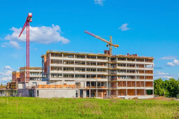 Byggnaden och kranar under konstruktion mot blå himmel — Stockfoto