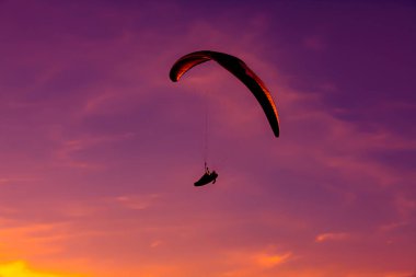 Paragliding ekstrem spor, Paraglider gün batımında mavi gökyüzünde uçan. 