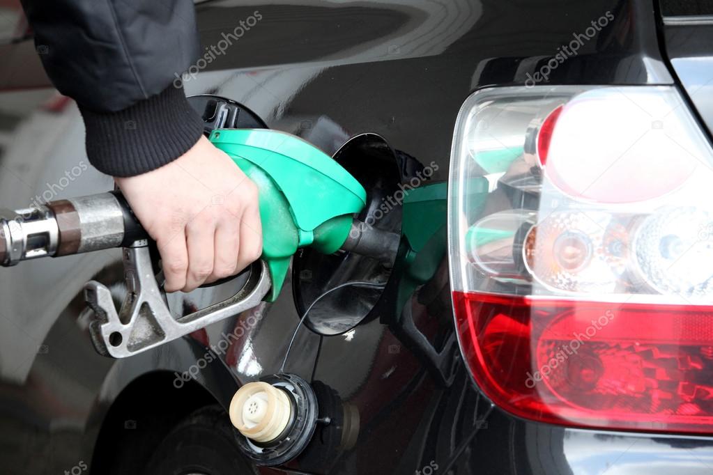Male hand refilling the black car with fuel on a filling station