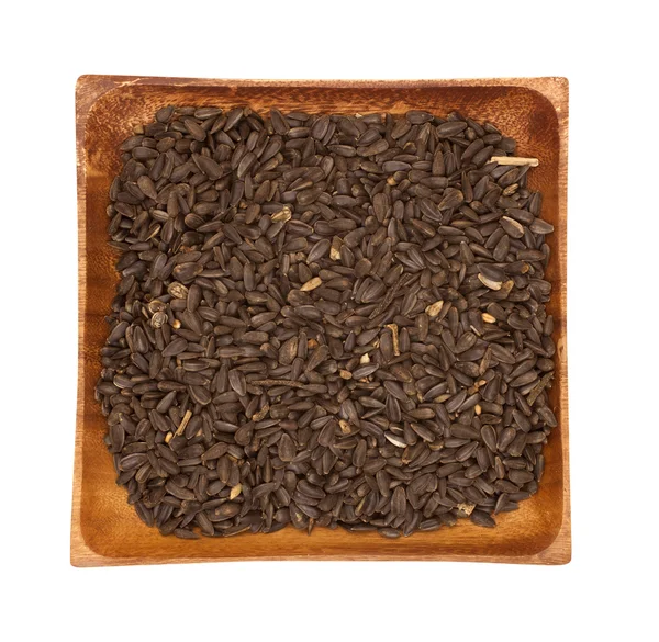 Ahşap kase beyaz zemin üzerine siyah ayçiçeği tohumu — Stok fotoğraf