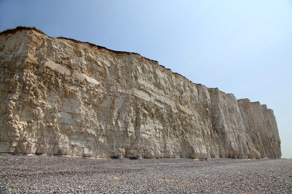 Beach head chalk cliffs and pebble beach against blue sky