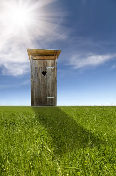 Ahşap tuvalet, yeşil alan, mavi gökyüzü