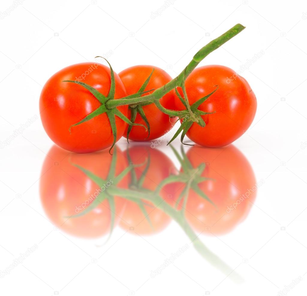Three fresh tomatoes with green leaves isolated on white background