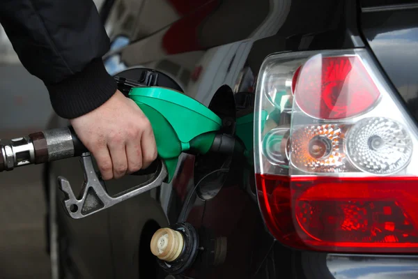 La mano masculina recarga el coche negro con combustible en una estación de llenado — Foto de Stock