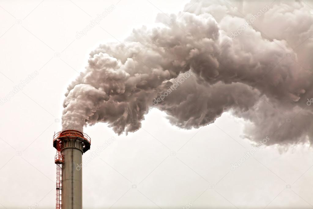 Closeup of dirty dark smoke clouds from a high industrial chimney