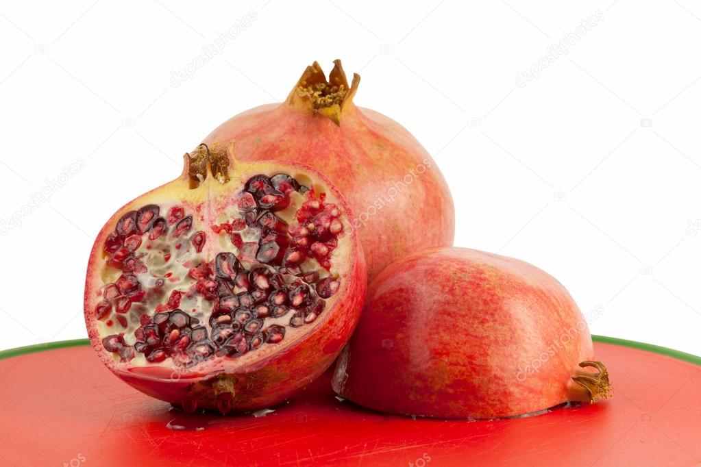 Ripe pomegranate isolated on red chopping board