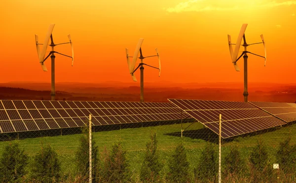 Paneles solares con pequeñas turbinas eólicas al atardecer —  Fotos de Stock