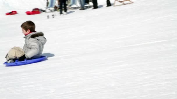 Câmera lenta duas crianças felizes que cai na neve com trenó — Vídeo de Stock