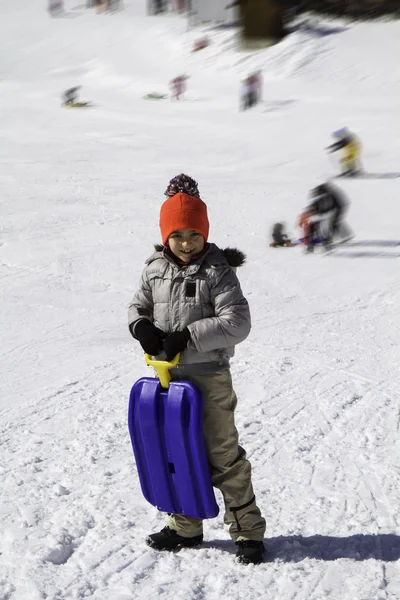 Bambino sulla neve con slittino blu — Foto Stock