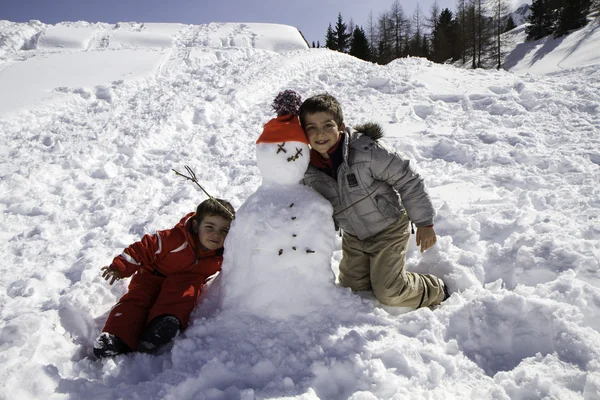 Two brothers with snowman — Stock Photo, Image