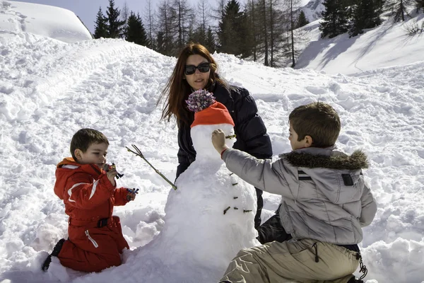 Two brothers and mother with snowman — Stock Photo, Image