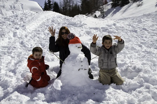 Due fratelli e madre con pupazzo di neve — Foto Stock