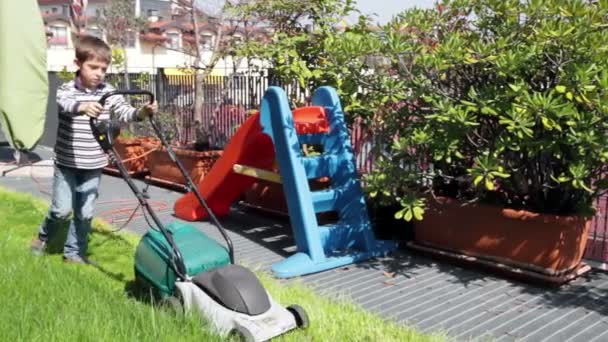 Kind met grasmaaier werken in de tuin — Stockvideo