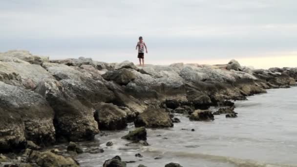Barnet går på vågbrytarna beach — Stockvideo