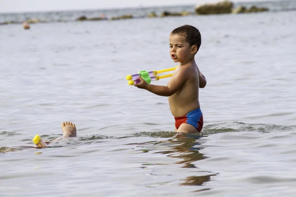 Niños felices juegan en el mar con watergun, vacaciones en Italia — Foto de Stock
