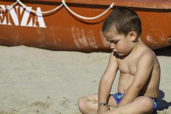Niño en la playa con bote de rescate — Foto de Stock