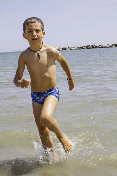 Niño feliz corre hacia el mar para nadar, vacaciones en Italia — Foto de Stock