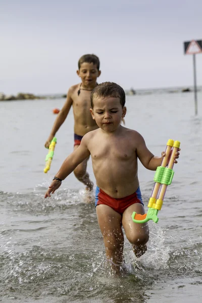 Crianças felizes brincam no mar com pistola d 'água, férias na Itália — Fotografia de Stock