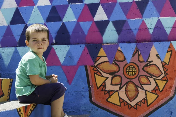 Portrait de petit garçon assis sur les marches et mur coloré — Photo